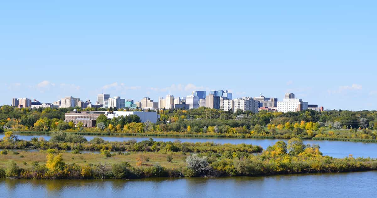view of the Regina skyline with office real estate behind a wooded area on the banks of a river
